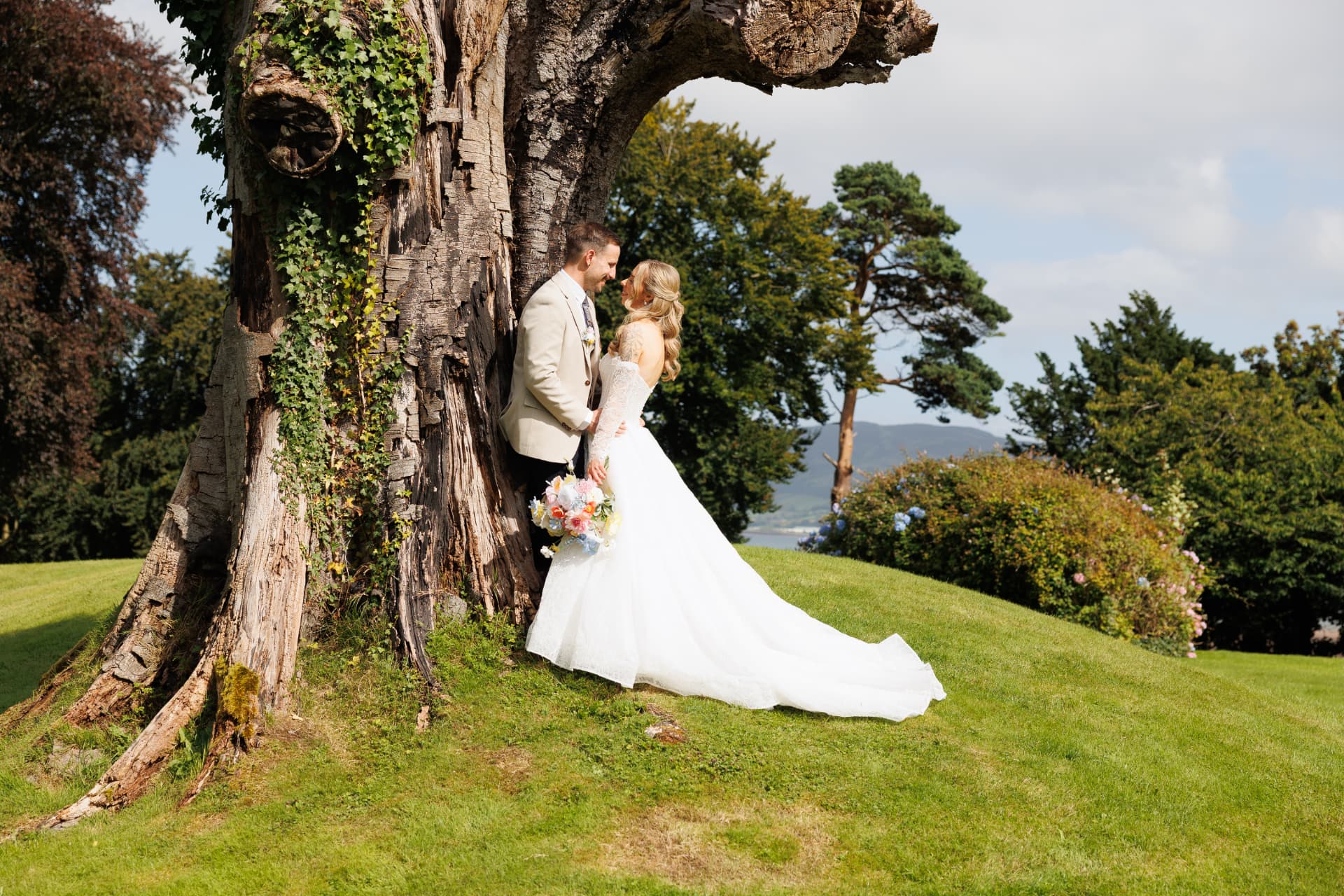 Bride and groom by an ancient tree with the lough behind