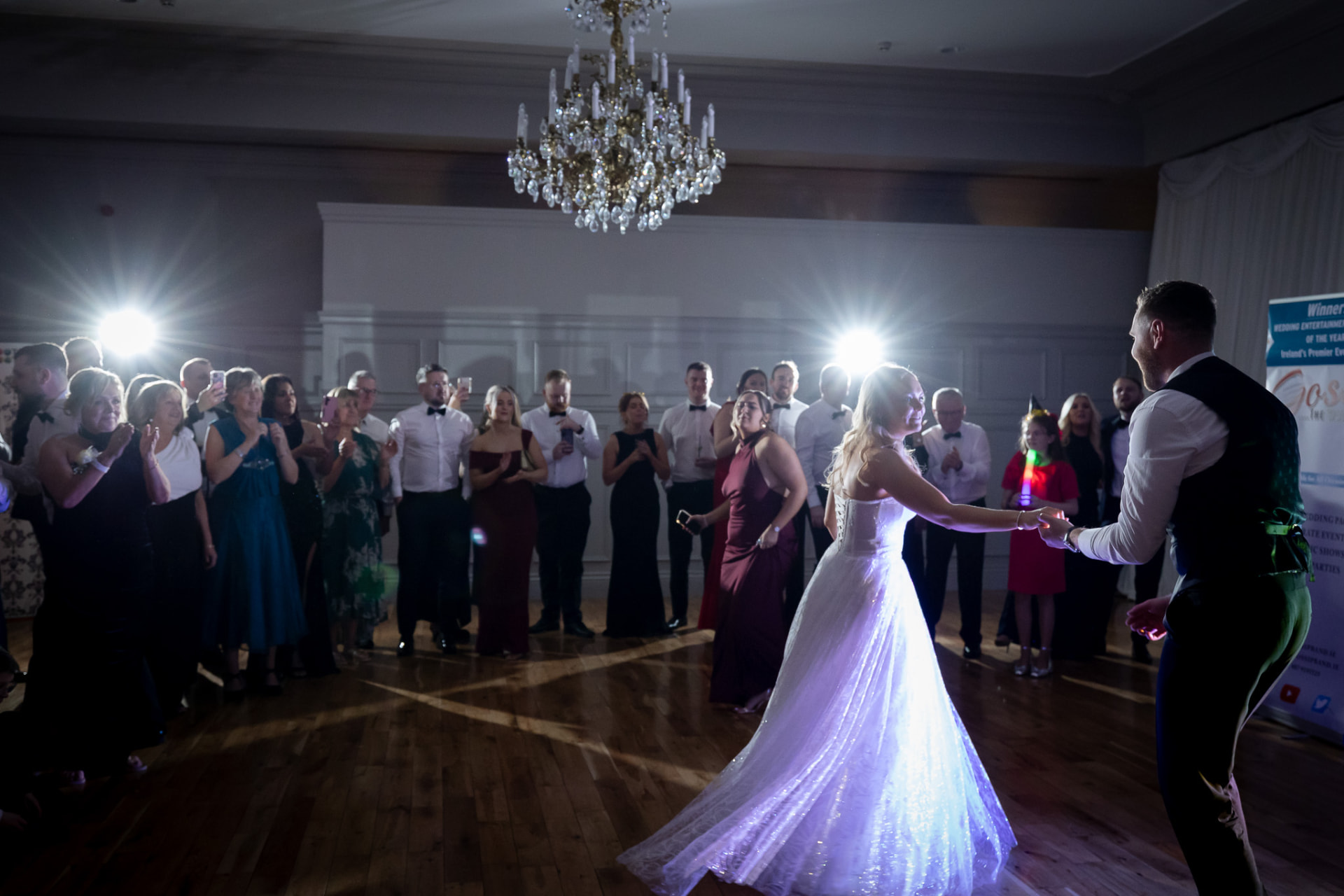 A bride and groom dancing at their wedding reception with guests watching.