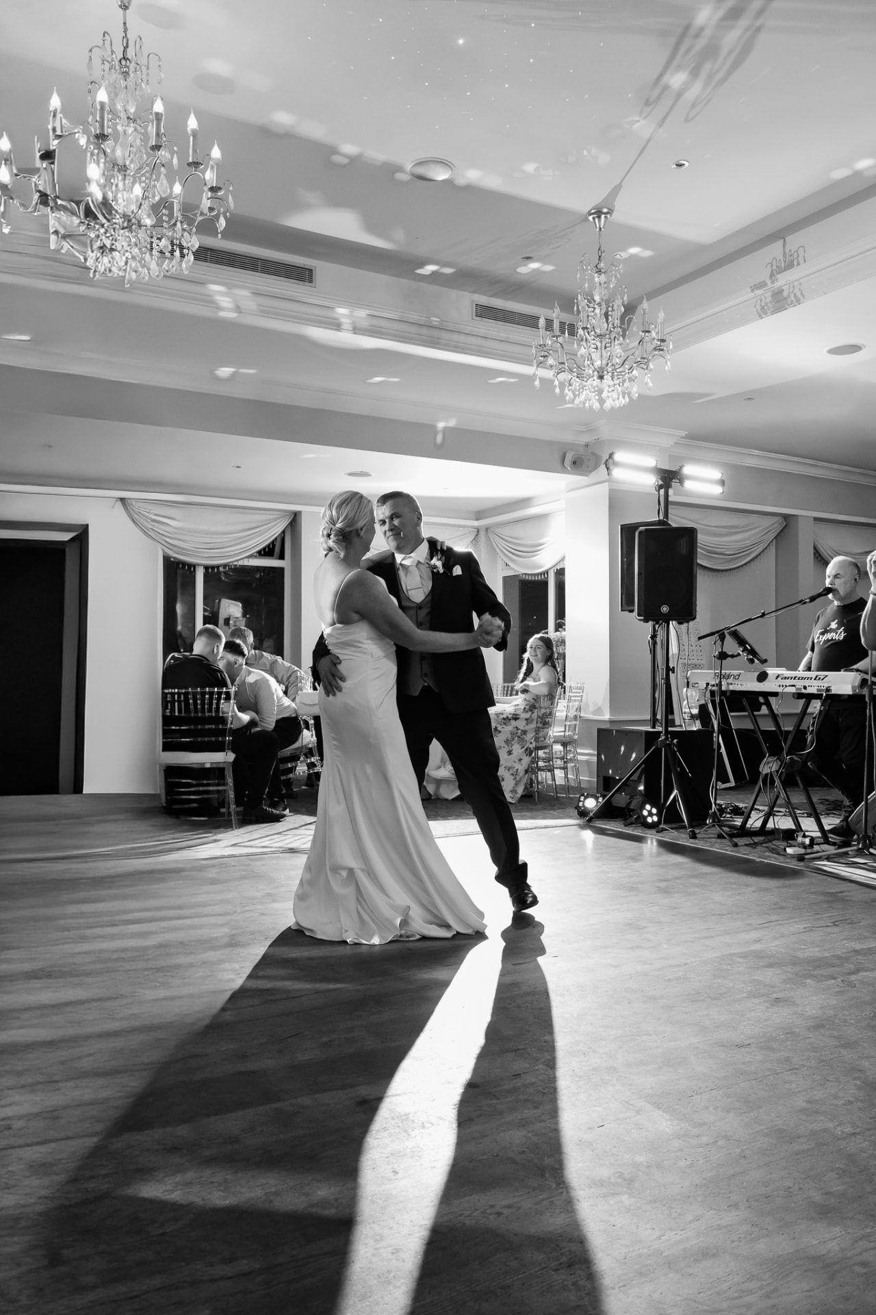 First dance beneath chandeliers, black and white