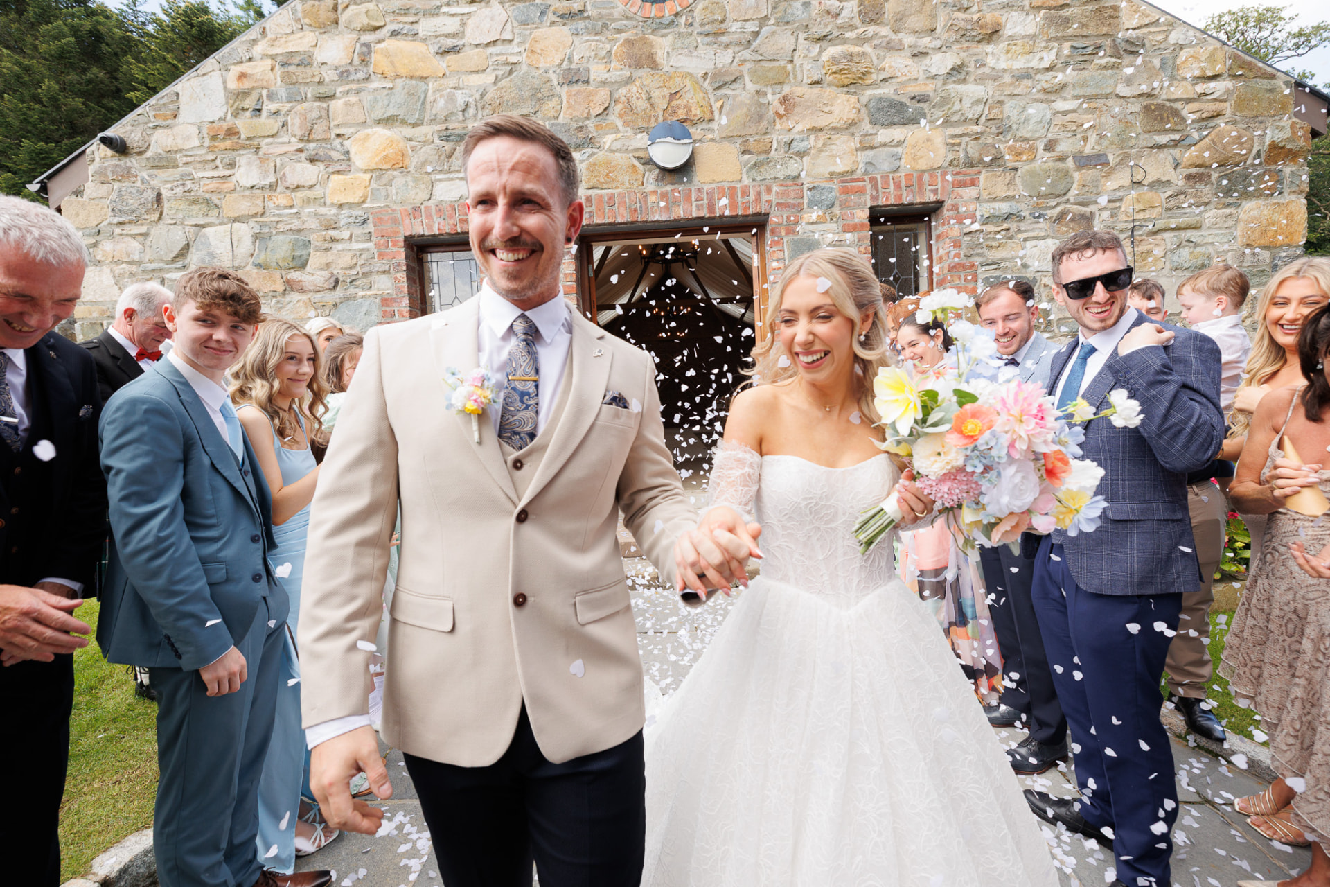 Bride and groom leaving the ceremony through a confetti shower