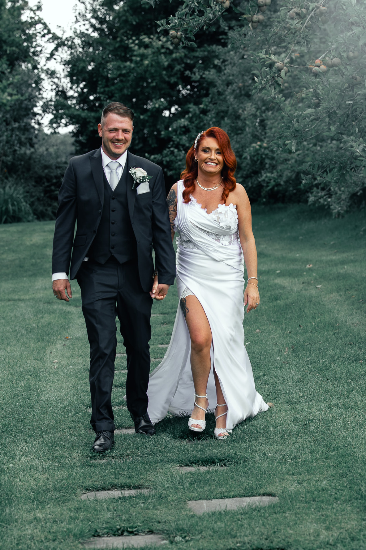Bride and groom walking hand in hand through an orchard