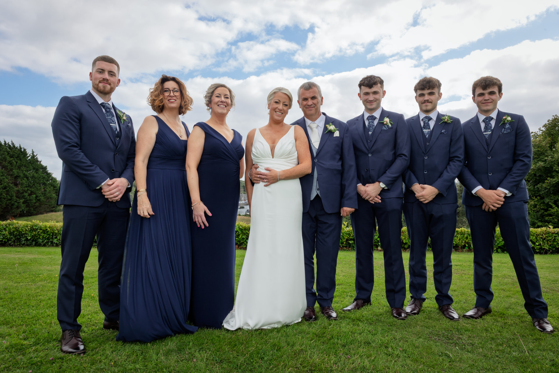 Bride and groom with family in navy on the lawn