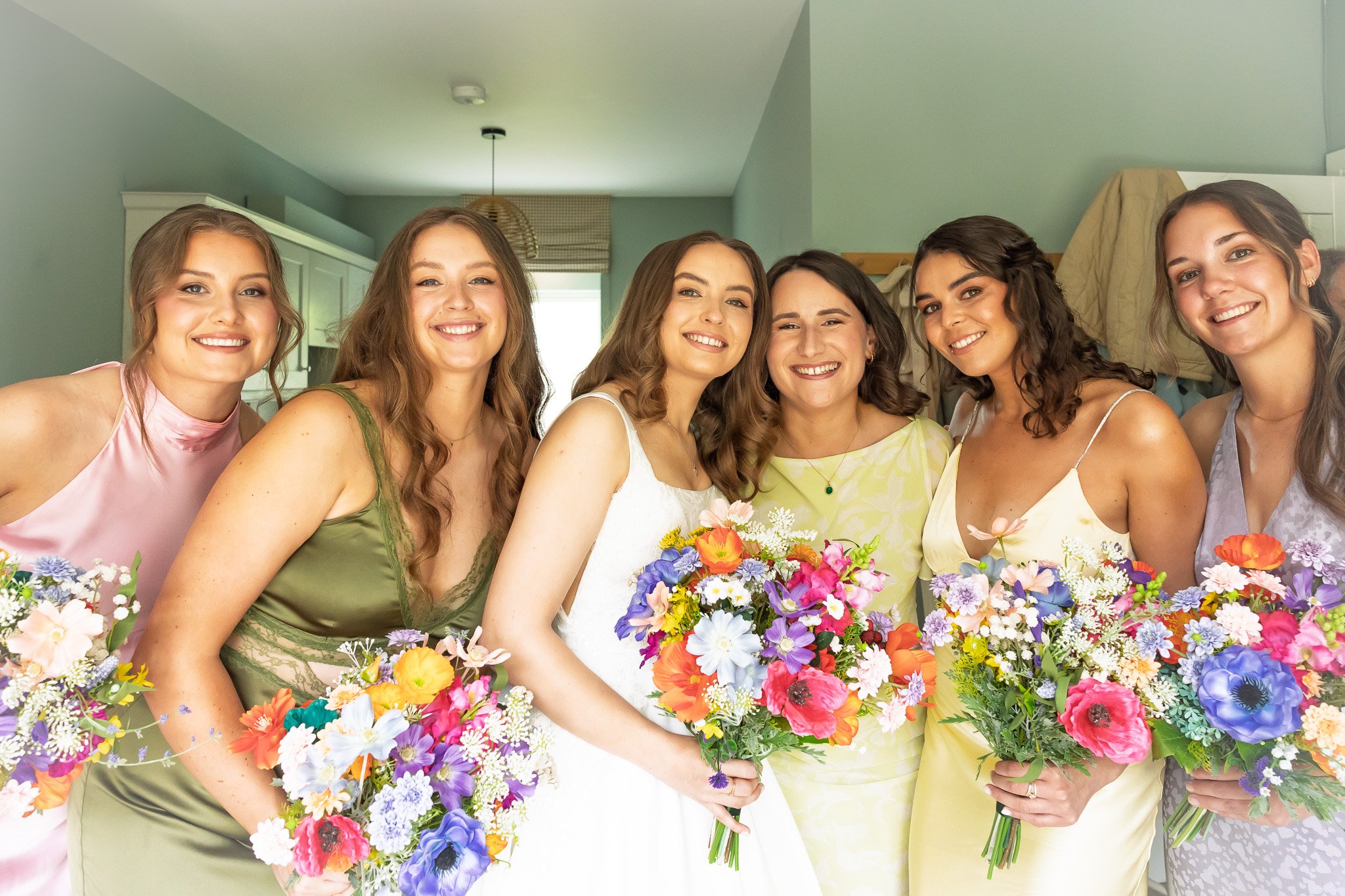 Group of women with bouquets of flowers, smiling indoors.