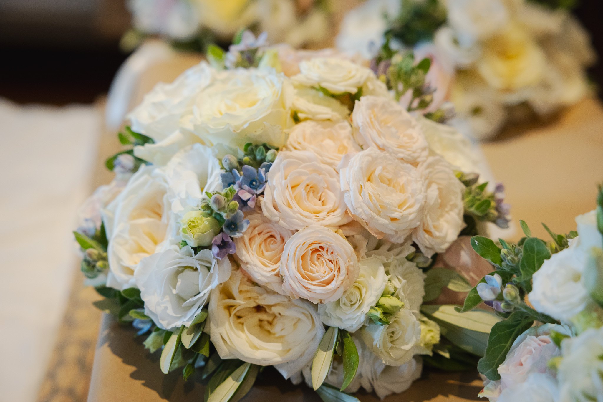 A bouquet of white roses, peonies, and small purple and green flowers