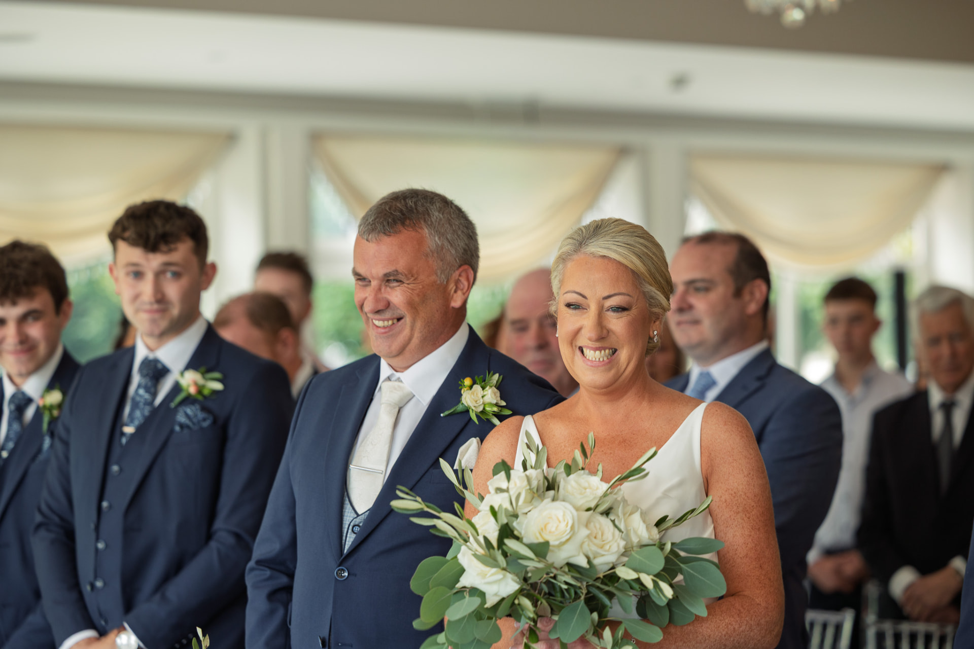 Bride walking down the aisle with her father as guests look on
