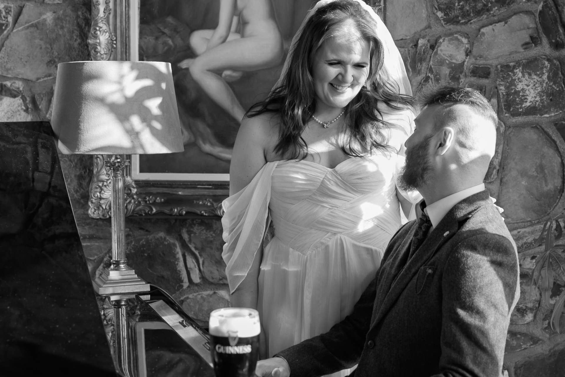 Bride and groom by the fireside with a pint, black and white