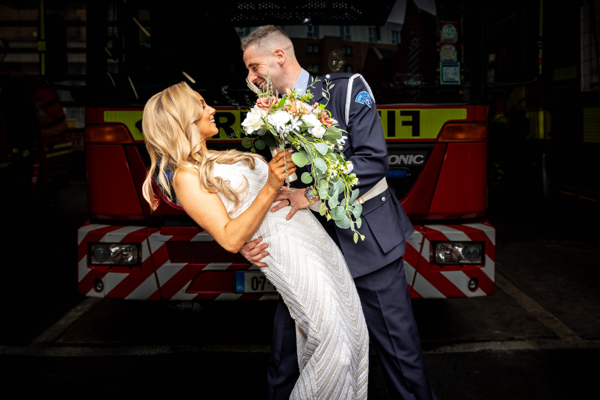Bride and groom laughing in front of a fire engine at a Dublin fire station